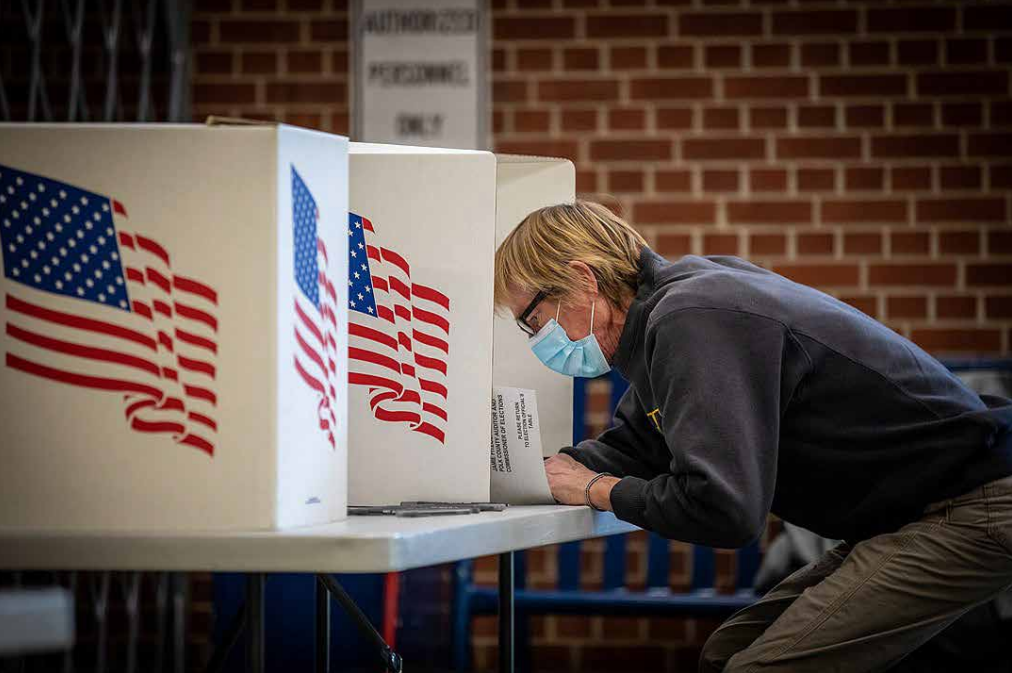 A man Voting while wearing a protective mask