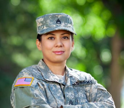 A female soldier stands with arms crossed.